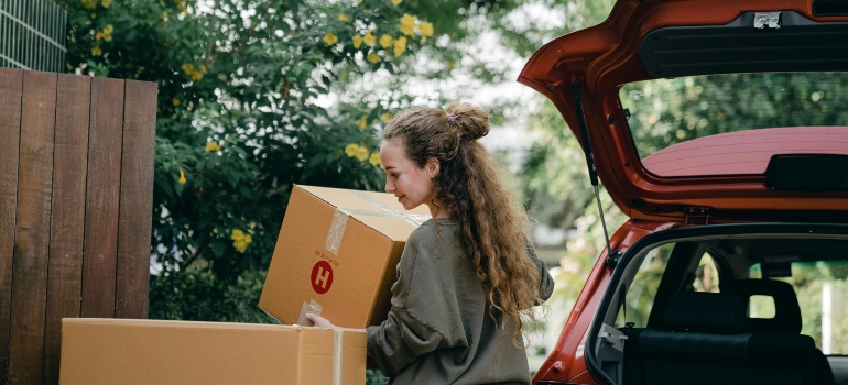 A woman is carrying boxes from her car to her new home.