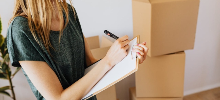 Person making a list next to cardboard boxes