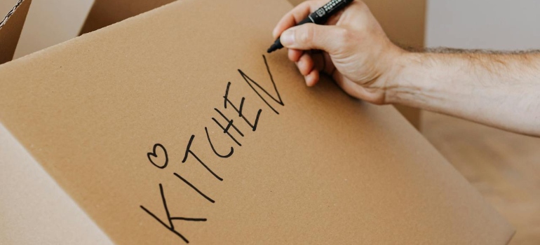 Person labeling a box before they prepare appliances for storage