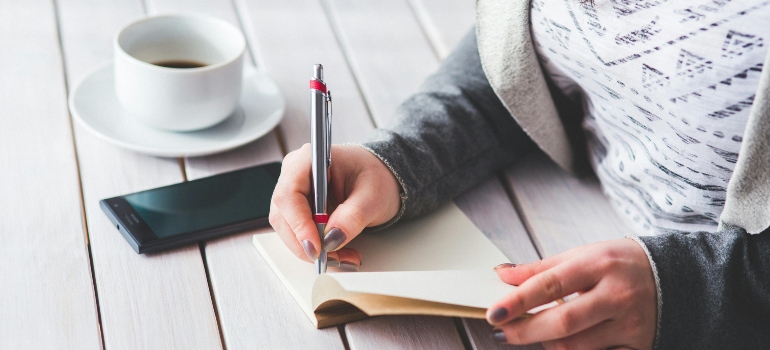 Person writing a checklist of questions to ask piano movers before the move
