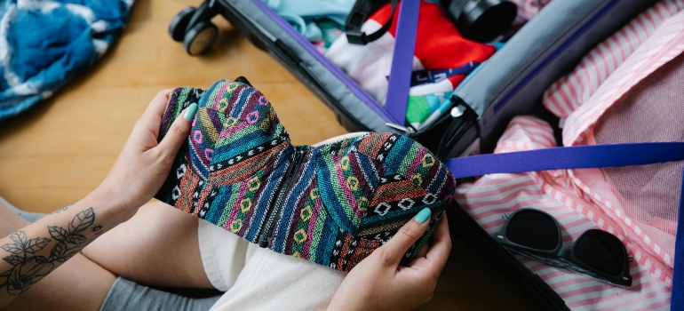 A person packing bright clothes and a camera into a suitcase for a Move from Mississauga to a Warmer Destination.
