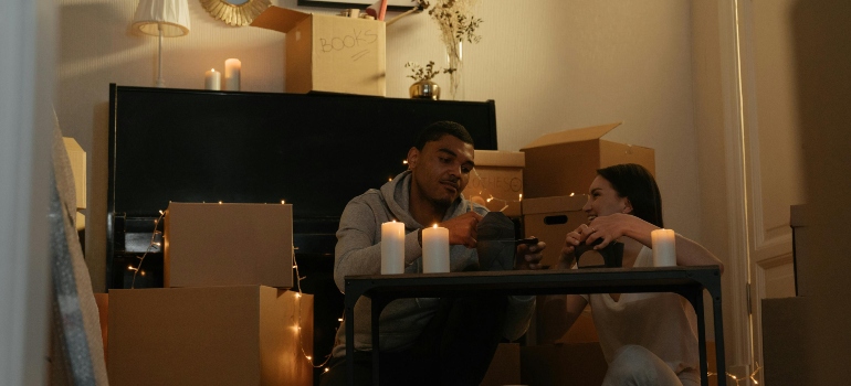 A couple is sitting in a room full of boxes.
