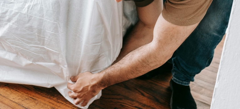 A man is covering the couch with blankets to safeguard hardwood floors during relocations.