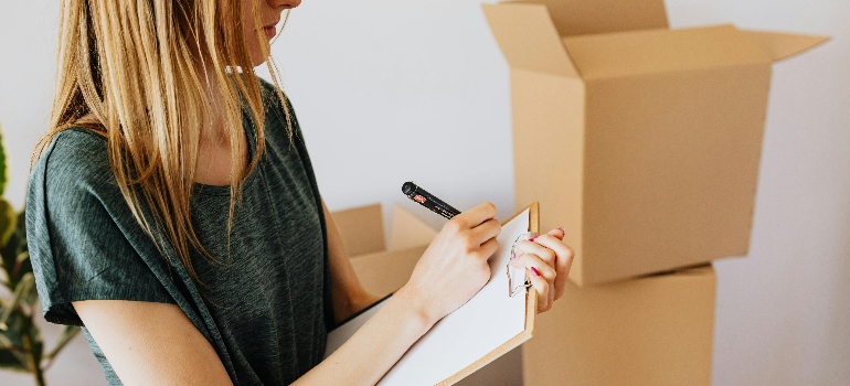 Woman creating an inventory list for storage unit organization.