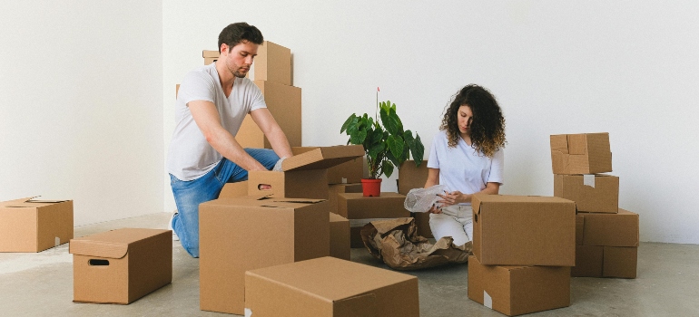 A couple is using cardboard boxes to pack their stuff, discussing the ideal green relocation.