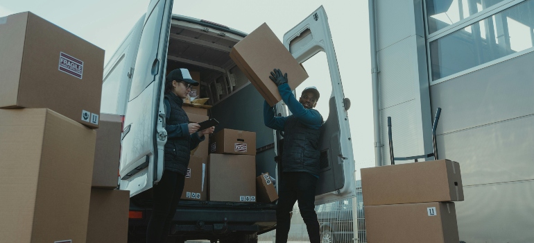 A movers are unpacking boxes out of the van.