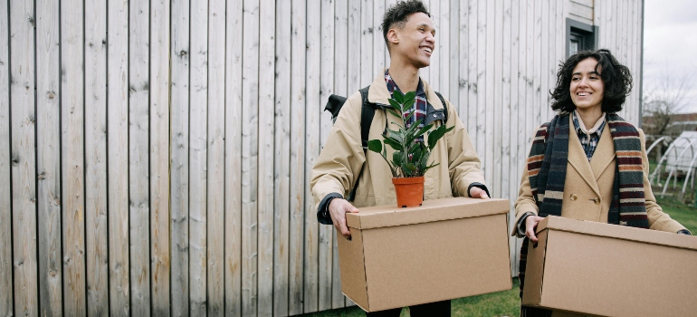 A smiling couple is holding the carton boxes, ready for the ideal green relocation.