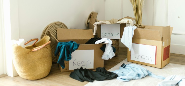 Labeled boxes sorted into donate, sell, and trash piles while preparing to move out