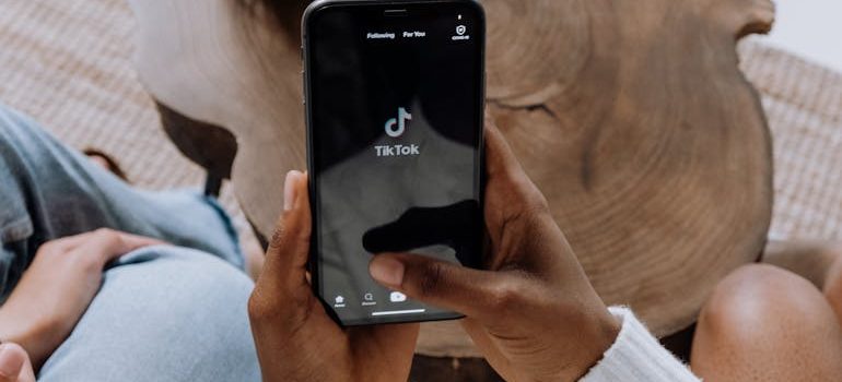 Person holding a smartphone displaying social media apps, representing sharing yard sale details online to reach local buyers.