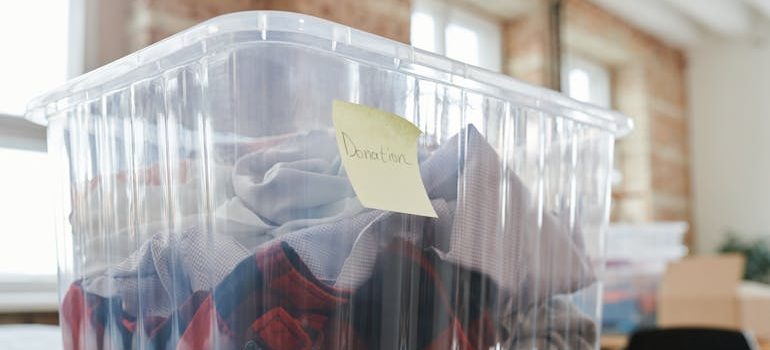 Clothes stored in clear plastic containers, representing the process of deciding what to sell, donate, or keep before a move.