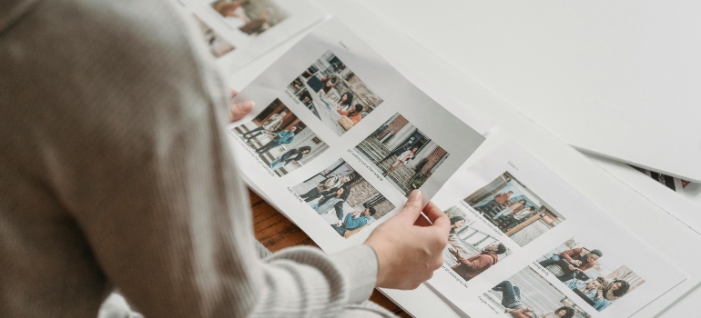 Crop unrecognizable woman looking through printed photos in album