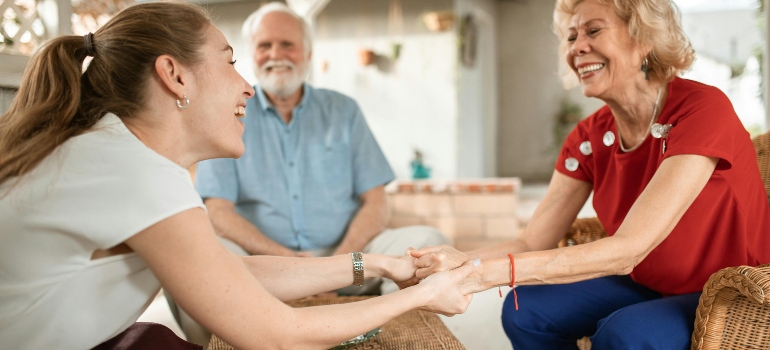 Young woman and her elderly parents talking and smiling while moving back in with your parents
