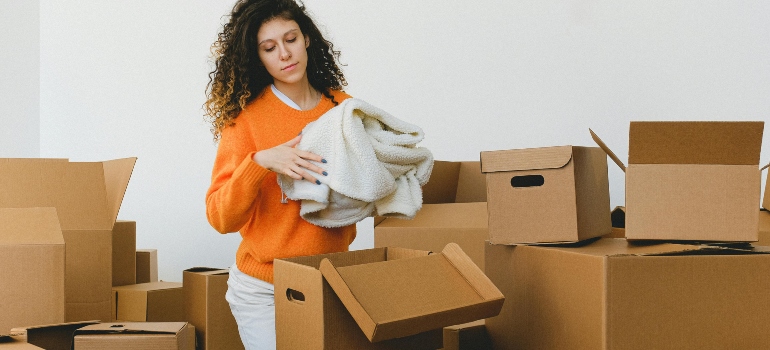 a woman packing items into cardboard boxes