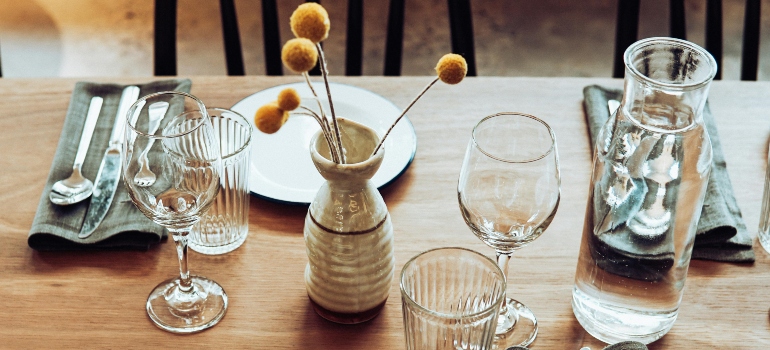 Wine glasses and glass pitcher arranged on a dining table, showing fragile kitchen items.