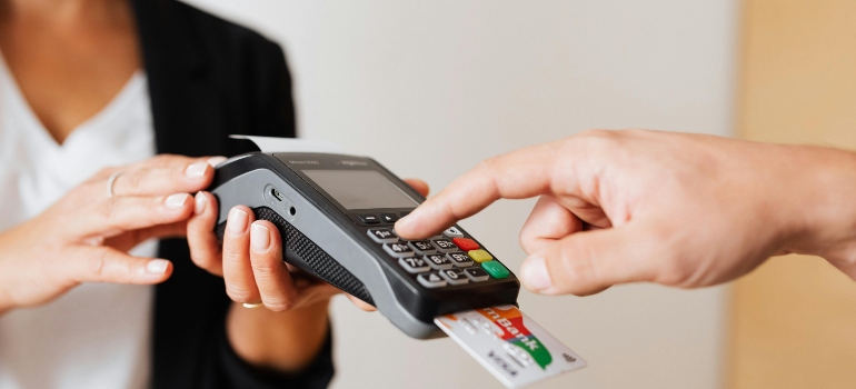 Client paying with card at payment terminal during booking process, highlighting financial planning and misconceptions about moving.