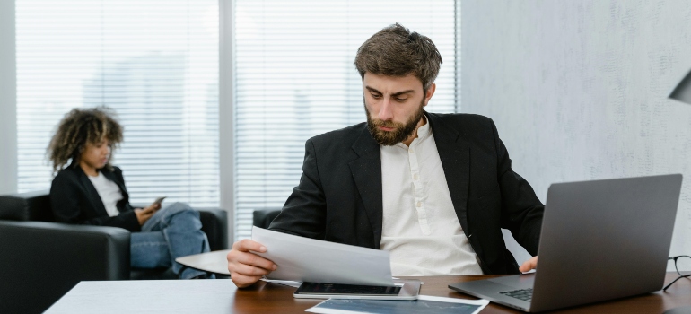 Client reviewing documents at office desk before signing agreement.