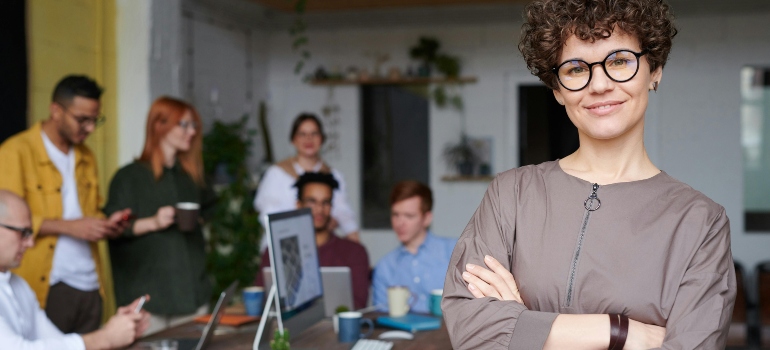 Business leader standing confidently in front of her team during office move preparation for a cost-effective business move with storage.