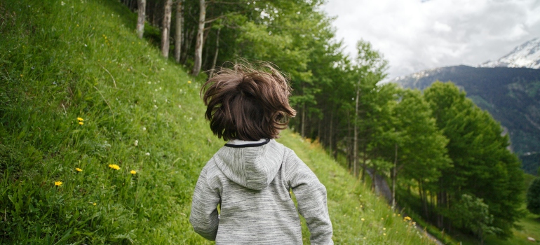 Toddler Wearing Gray Hoodie Running on Green Fields