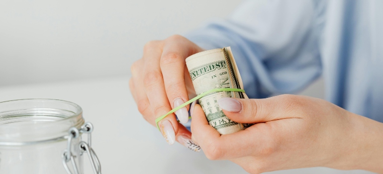 Hands holding cash to plan expenses while relocating to your first home.